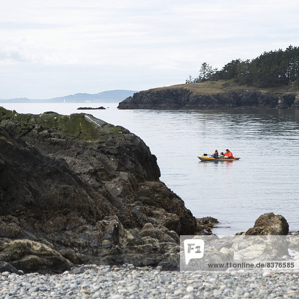 Three People In A Boat Off The Shores Of Deception Pass State Park  Washington  United States Of America
