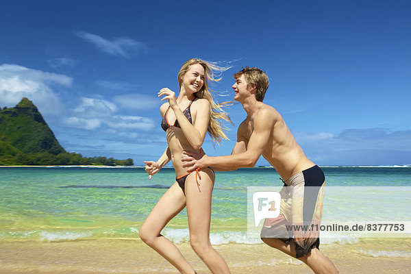 A young couple playing on the beach Wailua  Hawaii  United States of America