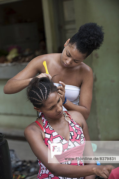A woman dressing a girlfriend's hair  Praia  Santiago Island  Cape Verde