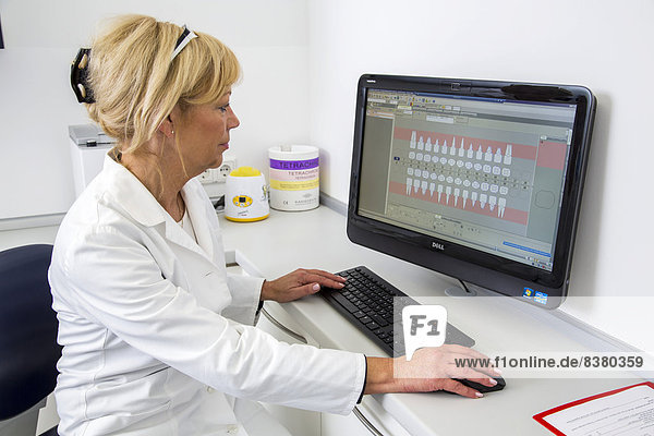 Dental assistant entering a patient's data into the electronic medical record  Germany