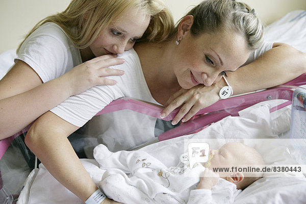 Mutter im Krankenhaus mit ihrer älteren Tochter und einem neugeborenen Baby