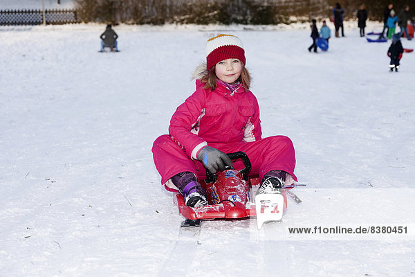 Girl sitting on a sled  Baden Wuerttemberg  Germany