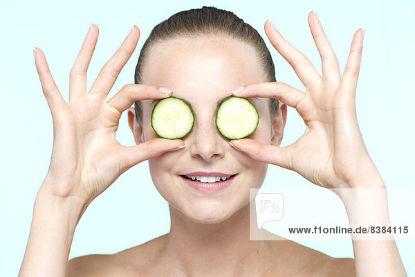 Woman holding cucumber slices on eyes