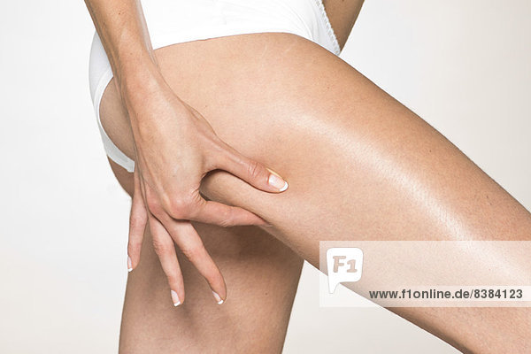 Woman in underwear  pinching back of thigh  cropped