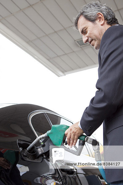 Geschäftsmann tankt Auto an der Tankstelle