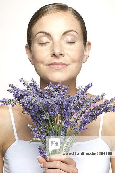 Woman smelling bouquet of fresh lavender with eyes closed