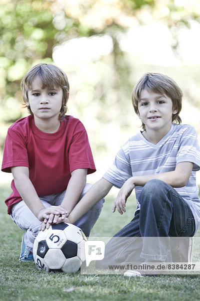 Jungen hocken auf dem Spielfeld mit Fußball Portrait