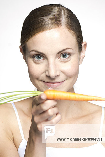 Young woman balancing carrot on hand  portrait
