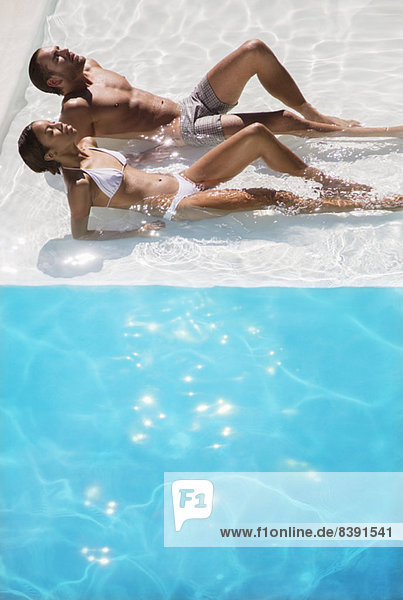 Couple sunbathing in swimming pool