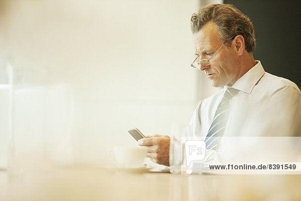 Businessman using cell phone in cafe