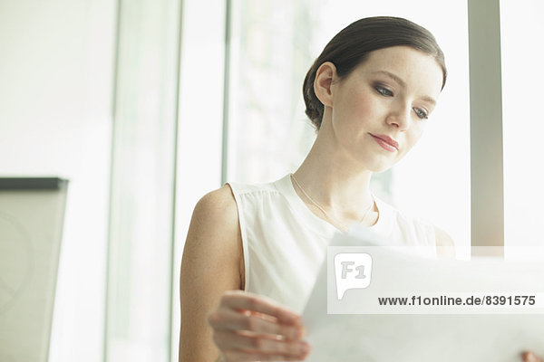 Businesswoman reading papers in office
