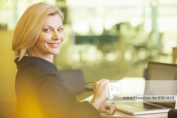 Geschäftsfrau lächelt am Schreibtisch im Büro