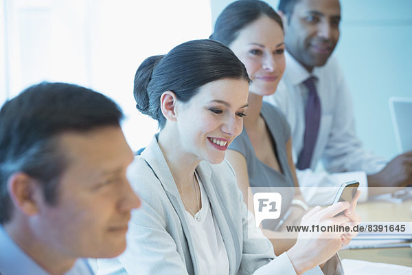 Businesswoman using cell phone in meeting