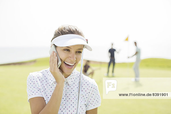Frau beim Telefonieren auf dem Golfplatz