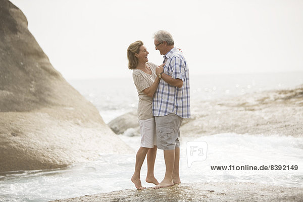 Seniorenpaar beim Umarmen am Strand