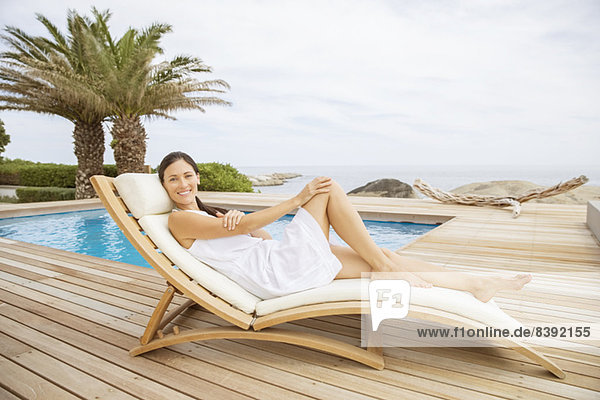 Frau entspannt sich im Liegestuhl am Pool