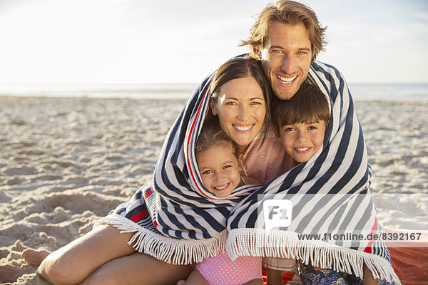 Family wrapped in blanket on beach