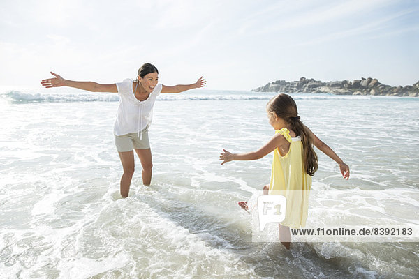 Mother and daughter playing in surf at beach