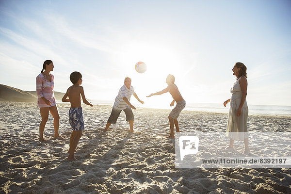 Multi-generation family playing volleyball on beach