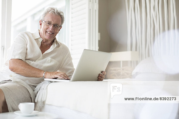 Older man using laptop on bed