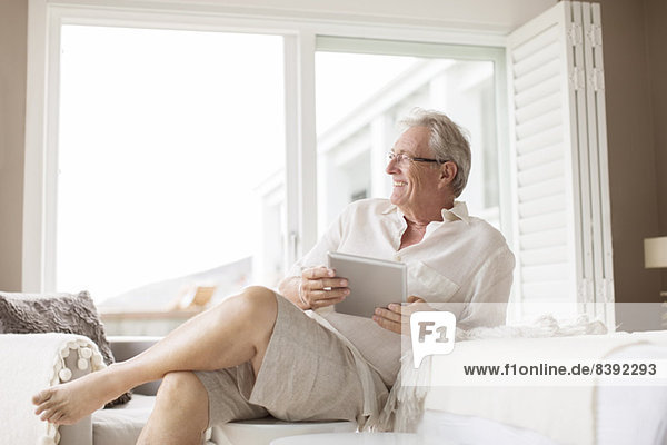 Älterer Mann mit digitalem Tablett im Schlafzimmer