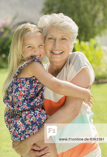 Older woman holding granddaughter in backyard