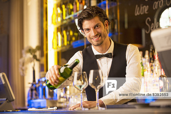 Porträt eines gut gekleideten Barkeepers  der in einer Luxusbar Wein ausschenkt.