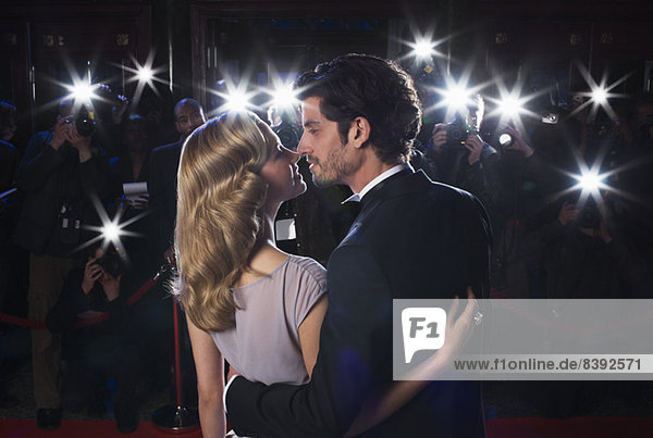 Paparazzi photographing celebrity couple kissing at red carpet event