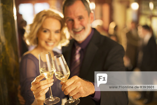 Porträt eines gut gekleideten Paares  das in der Theaterlobby auf Champagnergläser anstößt