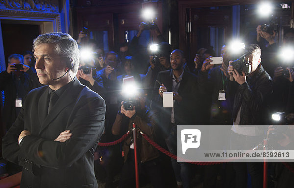 Paparazzi mit Blitzfotografie hinter dem Bodyguard bei einer Veranstaltung auf dem roten Teppich