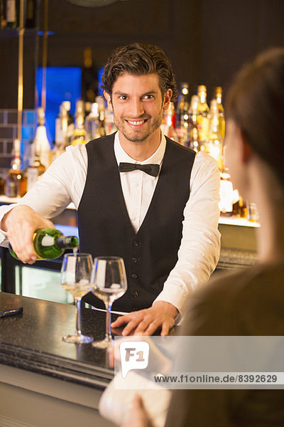Gut gekleideter Barkeeper mit Wein für den Kunden in der Luxusbar