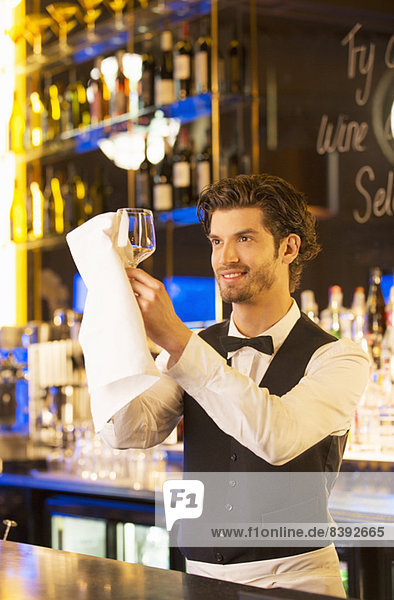 Gut gekleideter Barkeeper wischt Weinglas in der Luxusbar ab