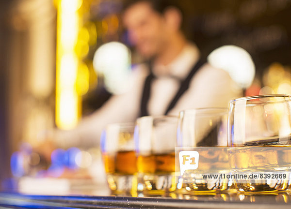 Nahaufnahme von Bourbon in Gläsern in einer Reihe an der Bar