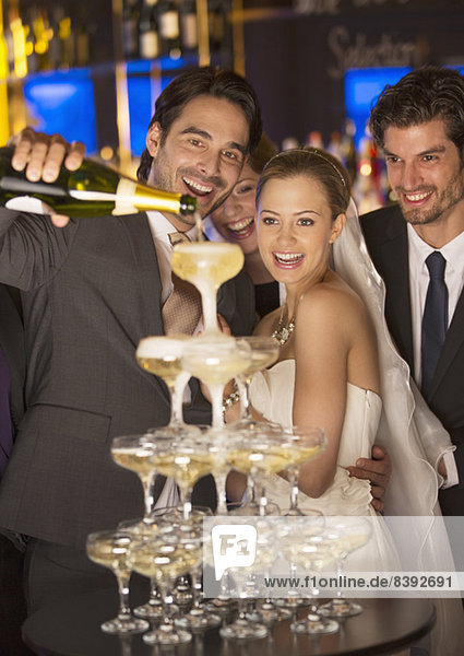 Bräutigam schüttet Champagnerpyramide bei der Hochzeitsfeier aus