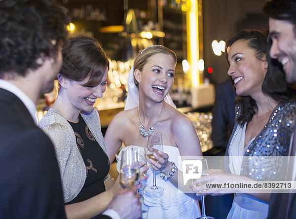 Fröhliche Braut trinkt Champagner mit Freunden bei der Hochzeitsfeier