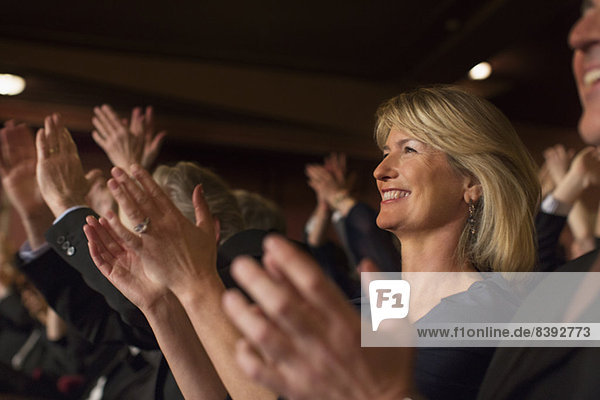 Close up of enthusiastic woman clapping in theater audience