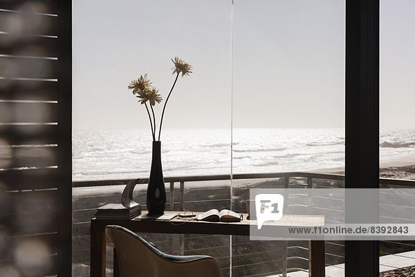 Blumenvase auf dem Schreibtisch im modernen Home-Office mit Blick auf den Ozean