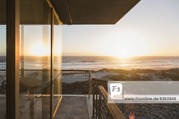Blick vom Balkon des modernen Hauses auf den Sonnenuntergang über dem Meer