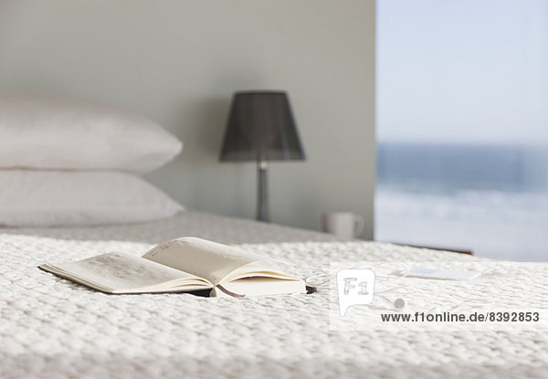 Buch und Gläser auf dem Bett im modernen Schlafzimmer mit Meerblick