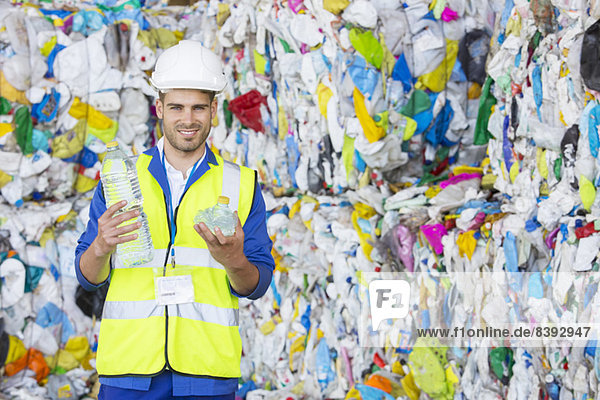 Arbeiter hält verdichtete Kunststoffflasche im Recycling-Zentrum