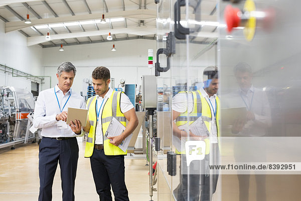 Supervisor und Mitarbeiter mit digitalem Tablett in der Fabrik