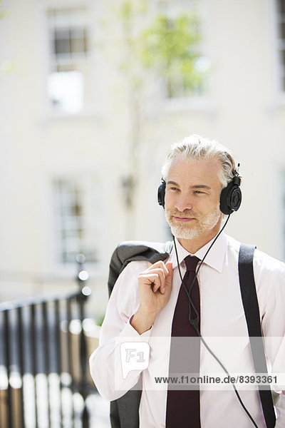 Businessman listening to headphones outdoors
