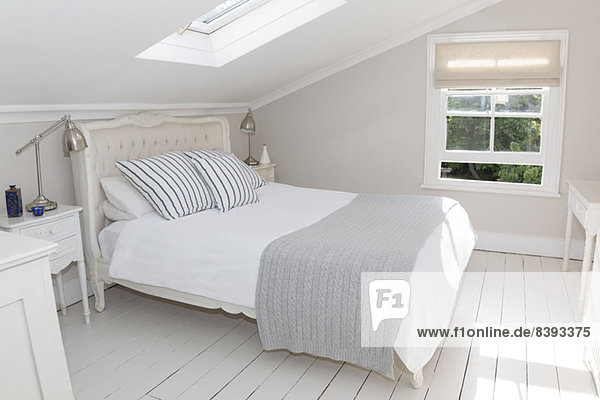 Bett im weiß getünchten Dachgeschoss-Schlafzimmer