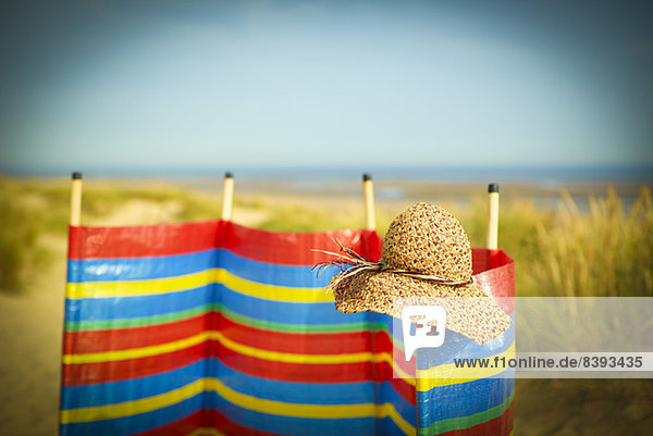 Strohhut auf Windschutz am Strand