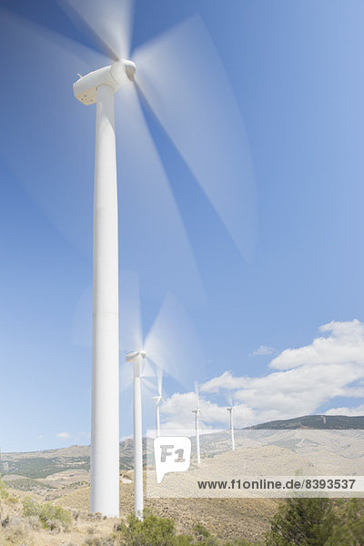 Windkraftanlagen drehen sich in ländlicher Landschaft