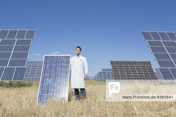 Scientist holding solar panel in rural landscape