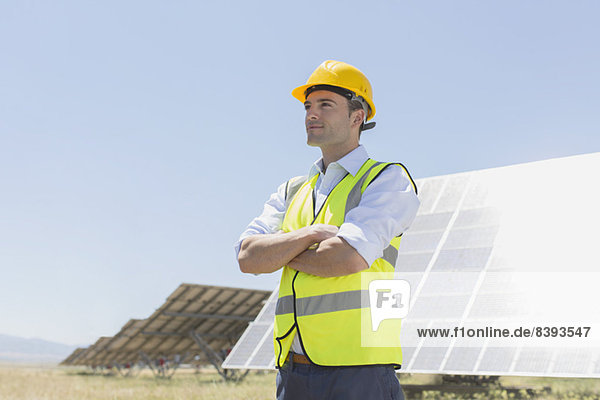 Arbeiter steht an Solarmodulen in ländlicher Landschaft