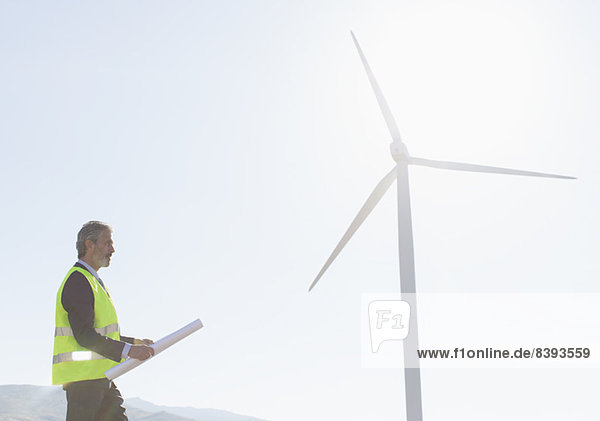 Arbeiter steht an der Windkraftanlage in ländlicher Landschaft
