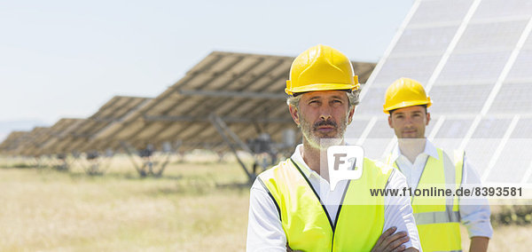 Arbeiter stehen an den Solarmodulen in der ländlichen Landschaft