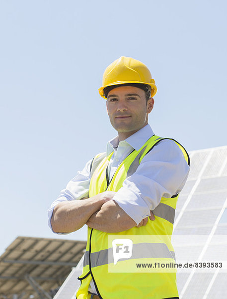 Arbeiter steht an Solarmodulen in ländlicher Landschaft